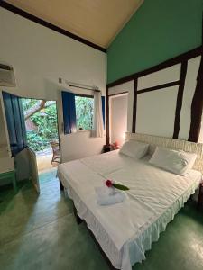 een slaapkamer met een wit bed met een bloem erop bij Pousada Marina de Boipeba in Ilha de Boipeba
