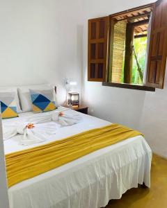 1 dormitorio con 1 cama blanca grande y ventana en Pousada Lumar, en Caraíva
