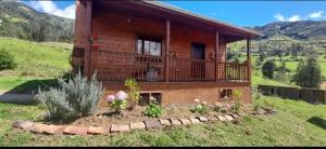 a house with a balcony and a garden in front of it at Rancho Valle del Rio in Cuenca
