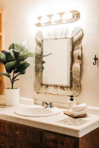 Group Getaway: Serene Adobe Retreat 4-11 guests في ألباكيركي: حوض الحمام مع مرآة وزرع الفخار