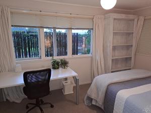 Schlafzimmer mit einem Schreibtisch, einem Bett und einem Fenster in der Unterkunft Feel at Home in Tauranga