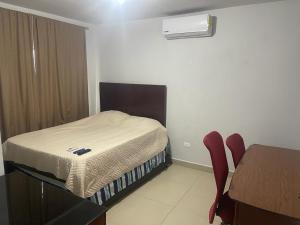 a small bedroom with a bed and a table and chair at Departamento Tranquilo NL in Monterrey