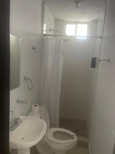 a white bathroom with a toilet and a sink at Departamento Tranquilo NL in Monterrey