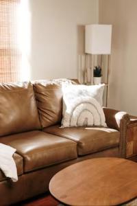 Group Getaway: Serene Adobe Retreat 4-11 guests في ألباكيركي: أريكة جلدية بنية مع طاولة في غرفة المعيشة