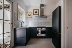 a kitchen with black cabinets and a sink and a stove at The Redbrick House in Castlemaine