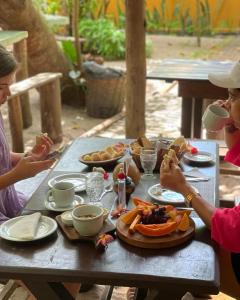 dos personas sentadas en una mesa de picnic comiendo comida en Pousada Lumar, en Caraíva