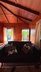 a living room with a couch and two windows at Cabañas Mahatua in Hanga Roa