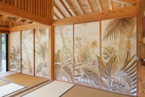 a wall of glass with a mural of plants at 泊まれるアートミュージアム 琉球ヴィラ in Tatsugo