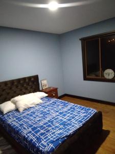 a bedroom with a bed with a blue wall at Rancho Valle del Rio in Cuenca