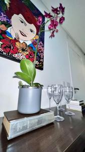 einem Tisch mit Weingläsern und einer Topfpflanze darauf in der Unterkunft Oásis Urbano com Netflix na Raja Gabáglia in Belo Horizonte