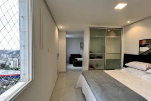 - une chambre avec un lit et une grande fenêtre dans l'établissement Oásis Urbano com Netflix na Raja Gabáglia, à Belo Horizonte