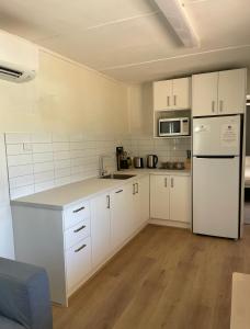 eine Küche mit weißen Schränken und einem weißen Kühlschrank in der Unterkunft Pichi Richi Park in Quorn