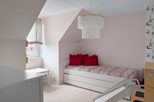 um pequeno quarto com uma cama com almofadas vermelhas em Radhus med 5 min bilavstånd till centrum & strand em Halmstad