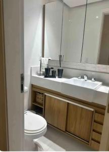 a bathroom with a sink and a toilet and a mirror at Apartamento na praia do Recreio - Posto 10 in Rio de Janeiro