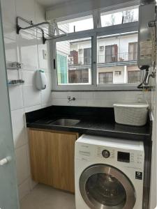 a kitchen with a washing machine and a sink at Apartamento na praia do Recreio - Posto 10 in Rio de Janeiro