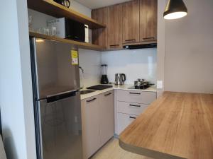 a kitchen with white cabinets and a stainless steel refrigerator at The Hood 102, Modern and Luxury Apartments in Bogotá +128 photos