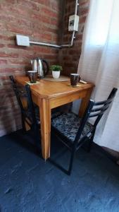 - une table en bois avec 2 chaises et une bouilloire dans l'établissement CABAÑA B COMPLEJO AIRES SERRANOS 2 a 3 PERSONAS TANTI, à Córdoba