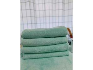 uma pilha de toalhas verdes sentadas no balcão da casa de banho em KAMEYA HOUSE ENOSHIMA - Vacation STAY 69765v em Fujisawa