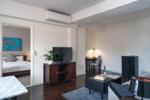 uma sala de estar com televisão e uma cama em Central Mansions Serviced Apartments em Phnom Penh