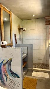 a bathroom with a shower with a painting of a dolphin at SHANTI SURF CAMP in El Paredón Buena Vista
