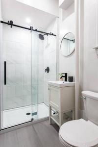 a white bathroom with a shower and a toilet at 4 Bedroom Sun Drenched & Designer Home in Brooklyn