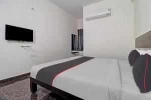 a white bedroom with a bed and a flat screen tv at 80977E SS Metro Ritz in Ameerpet