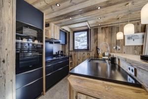 eine Küche mit Holzwänden und einer schwarzen Arbeitsplatte in der Unterkunft Residence La Canadienne - 5 Pièces pour 8 Personnes 554 in Val dʼIsère