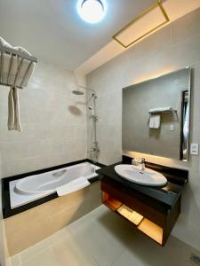 uma casa de banho com um lavatório e uma banheira em Rum Vang Hotel Da Lat em Da Lat