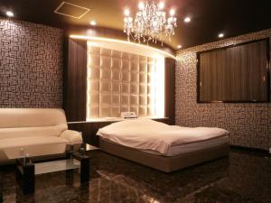 a bedroom with a bed and a chandelier and a chair at ホテルエーゲ海 - ラブホテル in Shizuoka