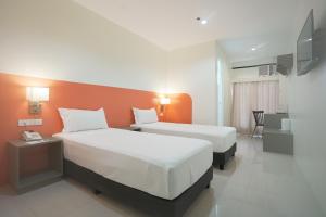 2 camas en una habitación de hotel con una pared de color naranja en Travelbee Airport Inn en Isla de Mactán
