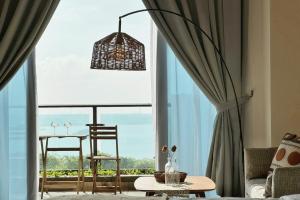 Habitación con ventana grande con 2 sillas y mesa. en Yussy Homestay at Carnelian Tower Forest City, en Gelang Patah