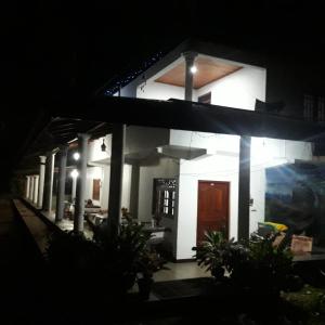ein weißes Haus mit brauner Tür in der Nacht in der Unterkunft Geeth Lanka River Resort in Matale