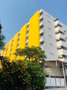 un edificio blanco y amarillo con árboles delante en S Ram Leisure Hotel SHA PLUS, en Bangkok