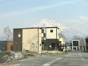 a building with a snow covered mountain in the background at Hirafu House 8 in Kutchan