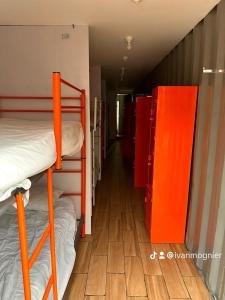 Ce dortoir comprend des lits superposés et des étagères orange. dans l'établissement Patio Hangar Toluca Aeropuerto (antes BoxPark), à Toluca