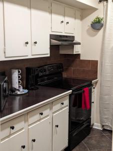 a kitchen with white cabinets and a black stove at The Comfort Zone in Baton Rouge