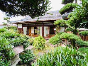 un giardino di fronte a una casa con cespugli di Guest House 古民家 NAGOMI a Izumisano