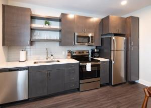 una cocina con electrodomésticos de acero inoxidable y armarios de madera en Cozysuites l Modern 1BR in Downtown Cincinnati, en Cincinnati