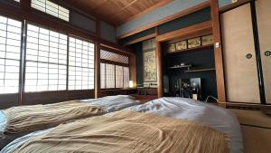 een groot bed in een kamer met ramen bij Guest House 古民家 NAGOMI in Izumi-Sano