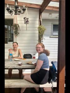 Due donne sedute a un tavolo su un portico di Tripinn Hostel Backpackers YHA a Westport