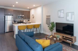 a living room with a blue couch and a kitchen at Cozysuites l Dream SDO in Downtown Cincinnati in Cincinnati