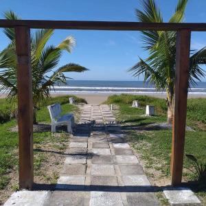 a stone pathway to the beach with a white chair at CASA 50 metros DA PRAIA Matinhos in Matinhos