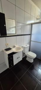 a white bathroom with a toilet and a sink at CASA 50 metros DA PRAIA Matinhos in Matinhos