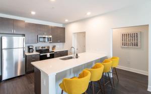 a kitchen with a white counter and yellow bar stools at Cozysuites l Luxe 2BR in Downtown Cincinnati in Cincinnati