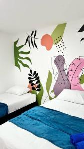 a bedroom with two beds with a mural of plants at Apartamento Marbar 1 in Cartagena de Indias