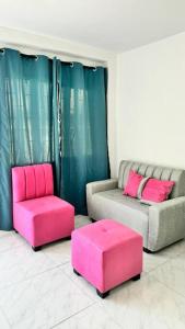 a living room with two chairs and a pink ottoman at Apartamento Marbar 1 in Cartagena de Indias