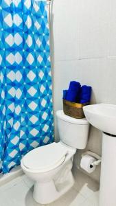 a bathroom with a toilet and a sink with a blue shower curtain at Apartamento Marbar 1 in Cartagena de Indias