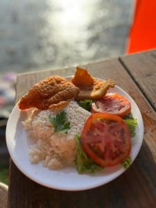 a plate of food with rice and tomatoes on a table at Pousada Alto da Prainha in Rio de Janeiro