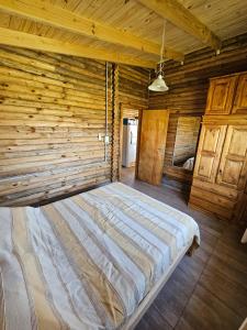a large bed in a room with a wooden wall at Campo Cuyen, Cabañas in Lobos