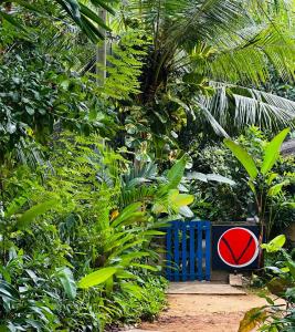 a blue bench with a red sign in a forest at VIEW guesthouse & bistro at goyambokka in Tangalle